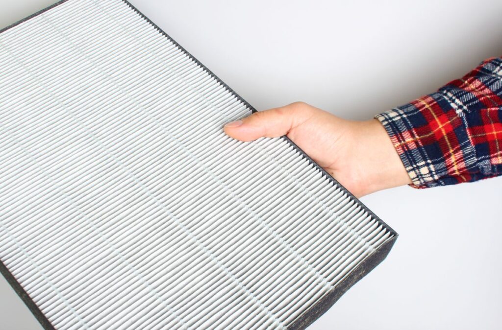 best air filter for home hand holding filter against wall