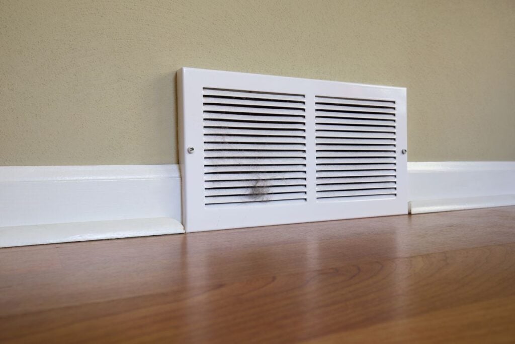 Dirty register wall vent with pet hair clogging the duct opening in a home