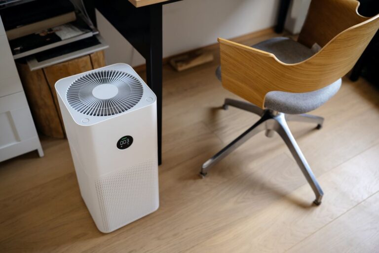 air purifier in the interior next to the workplace and armchair, cleaning from fine dust in the house