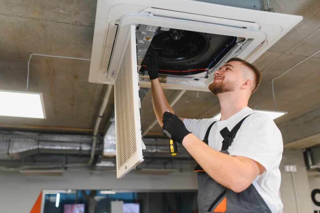 commercial air vent cleaning worker looking into hole