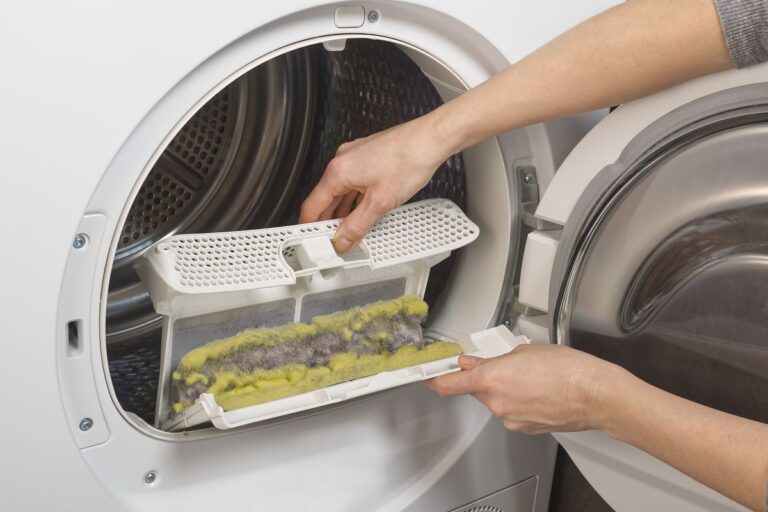 how to clean dryer lint trap hand holding trap in front of white machine