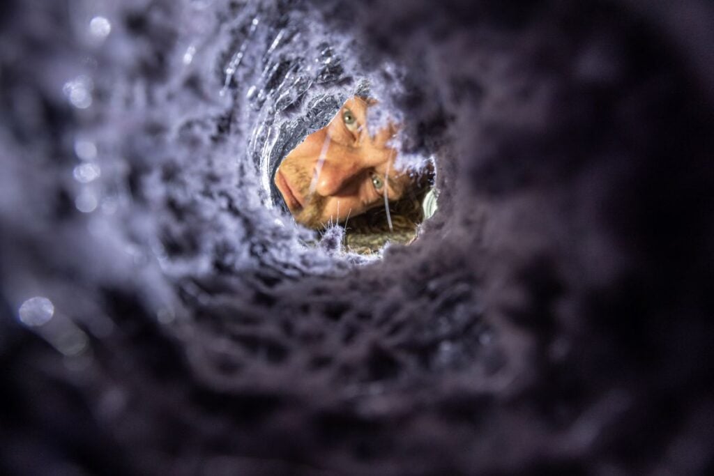clogged dryer vent worker looking inside pipe