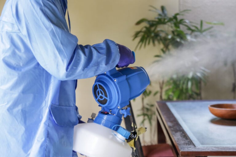 professional disinfection services worker using blue suit inside house with desfinfecting machine